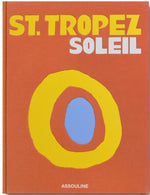 Book cover titled "St Tropez Soleil" in bold yellow and white letters on an orange background with abstract circular shapes in yellow, blue, and orange. The publisher's name "Assouline" is at the bottom. Whether you're dreaming of Nikki Beach or the elegance of Les Voiles de Saint-Tropez, this cover captures the essence of St. Tropez.

