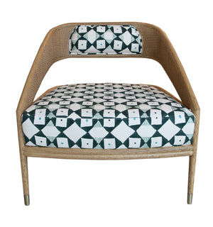 Experience the exquisite Tenan Lounge Chair in Broadway, a wooden armchair featuring a geometric patterned cushion and backrest. The pattern boasts black, white, and teal diamonds and squares. Enhanced with a rattan frame and Blonde Brass finish, it’s the epitome of stylish comfort.