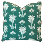 The Mazari Palm Outdoor Pillow features a green square design with white tropical palm tree and bird patterns on weather-resistant fabric, adding style and comfort to your outdoor space. Shown on a plain white background.