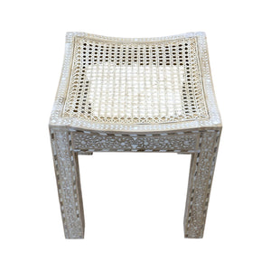 The Cane Stool features an intricately carved wooden frame and a woven cane seat, shown against a white background.