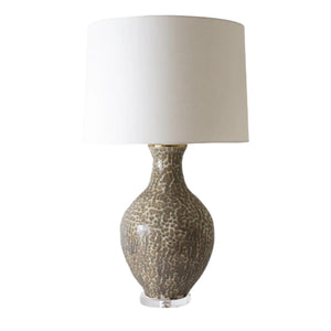 The Athens Large Brown Dappled Lamp features a textured brown ceramic base and a large white cylindrical shade, highlighting artistic excellence against a white backdrop.