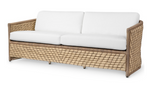 The Capitola Sofa features a light brown synthetic seagrass wicker frame and white seat and back cushions, displayed against a white background.