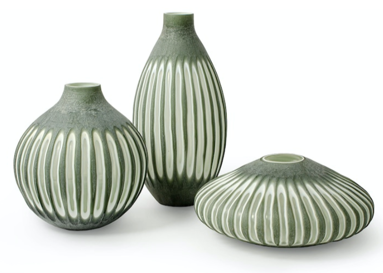 The Aster Vase Collection includes three green ceramic vases with vertical white stripes and hand-etched sides, each in a different shape: one is squat and round, another is taller and oval, and the third is flat and wide.