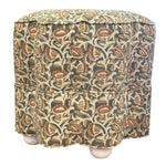 The Stella Stool in Marbella Linen Eucalypt on White is a square, upholstered ottoman with floral-patterned fabric and white bun-shaped legs, perfect for compact seating or use as a stylish accent stool.