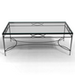 The Amalfi Glass Top Cocktail Table features a tempered glass surface and a hand-forged steel frame with bold geometric patterns.