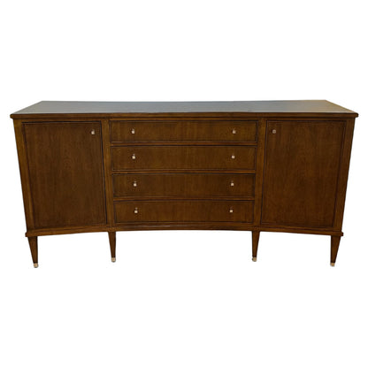 The Smithson Sideboard is a mid-century modern wooden piece featuring four central drawers, two side cabinets, antique silver hardware, and tapered legs—ideal for stylish dining storage.