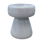 The Mushroom Stool features a glossy, light gray porcelain finish, a round flat top, and a wide conical base in a unique mushroom shape. It's shown against a white background.