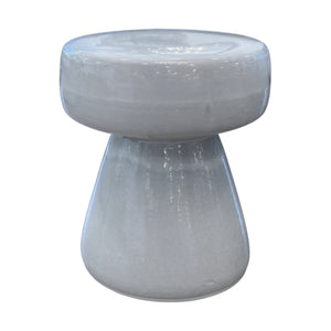The Mushroom Stool features a glossy, light gray porcelain finish, a round flat top, and a wide conical base in a unique mushroom shape. It's shown against a white background.
