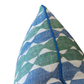 Close-up of the Whittle Blue Green Lumbar Pillow corner, showcasing vibrant blue and green wavy patterns with a refined blue piping edge, set against a white background. This custom pillow also features a hidden zipper closure for a seamless finish.