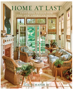 Cover of the book "Home At Last: Enduring Design for the New American House" by Gil Schafer III. Features a sunlit, cozy living room with wicker furniture, plants, and a view of greenery outside, embodying contemporary traditional architecture.