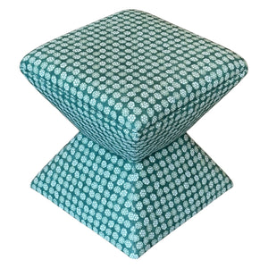 The Hamilton Outdoor Ottoman in Boheme Green features a geometric design with teal and white upholstery, a square seat, and a tapered base—ideal for enhancing your patio decor.
