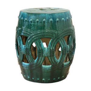 The Circle Garden Stool in Green and Turquoise features an intricate cutout design and glossy finish, offering an antique-inspired look with timeless outdoor charm.