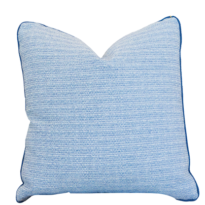 The Roxam Blue Pillow is a square, light blue woven pillow with subtle horizontal stripes and dark blue piped edges. It features a hidden zipper closure for a seamless look and is showcased against a white background.