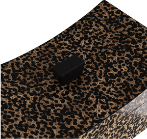 Close-up of the Yarin Box, a rectangular black button displayed on a patterned surface reminiscent of leopard print, evoking the elegance of an ancient Chinese empire pillow.