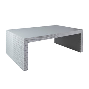 The Lance Coffee Table features a smooth gray rectangular top and a textured, brick-like pattern along its sides and legs, set against a plain white background—a striking piece of contemporary living room furniture.