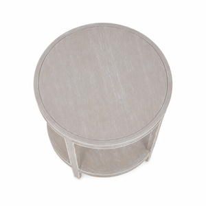 The Greenwich Chairside Table is a compact round table with a light, weathered finish, straight legs, and a handy lower shelf—versatile as an accent piece and shown from above.