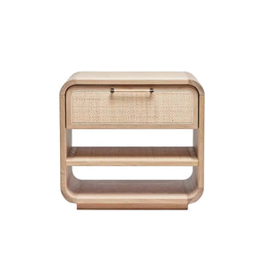 The Marsh Bedside Chest features a wooden build with rounded edges, a single drawer with a blonde rattan front, and two open shelves underneath.