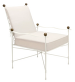 The Janus et Cie Amalfi Lounge Chair in White Vermouth with Asti Cushion is inspired by Etruscan design, featuring a white metal frame, square seat and back cushion, and round dark finials on the armrests and corners.