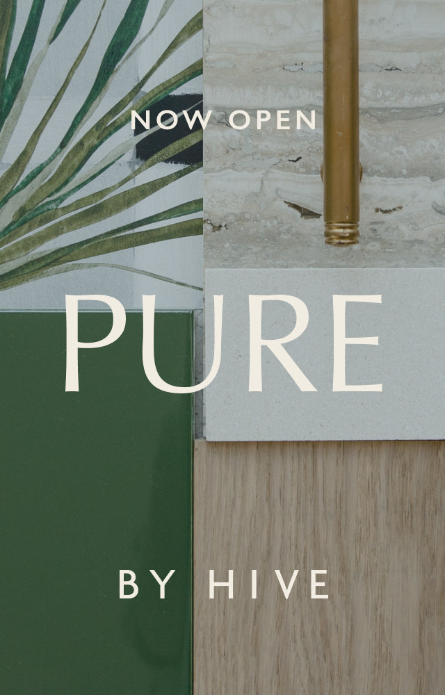 A mobile orientated image of Pure by Hive design scheme utilizing natural, tropical hues with a palm leave wallpaper, rich green tile and modern brass hardware.